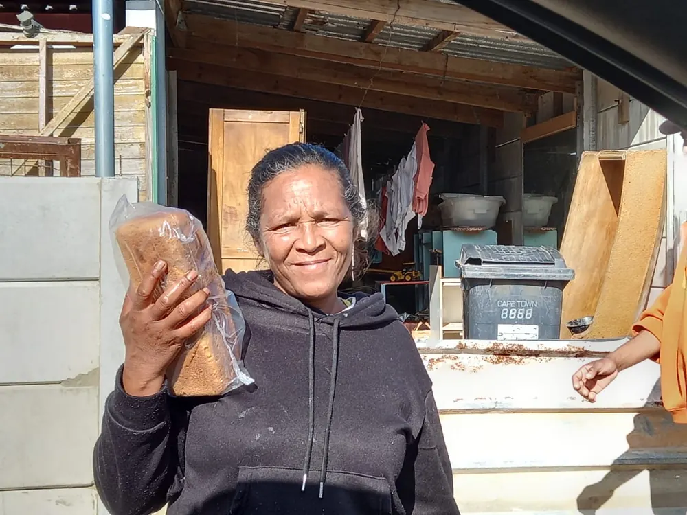 A smiling woman holds up a loaf of Artos bread